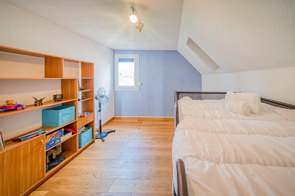 chambre pour enfants, ados, ou jeunes adultes avec un 2 lits superposés et une étagère de rangement à l'étage