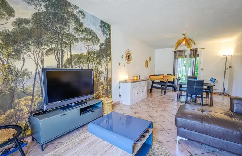 Salon / salle à manger vue sur la piscine avec une grande table à manger pour 8 personnes, un grand canapé d'angle, une TV HD et un babyfoot