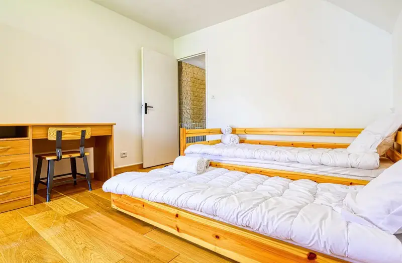 chambre avec 2 lits simples, un futon pour 2 personnes, une étagère de rangement et un bureau à l'étage 